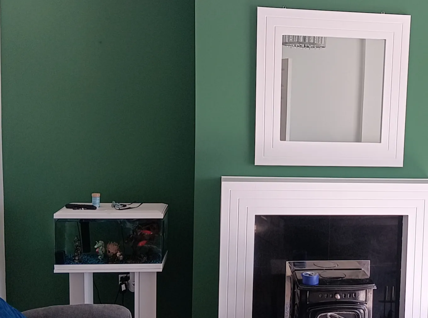 Green feature wall with white panelled mirror and fireplace surround