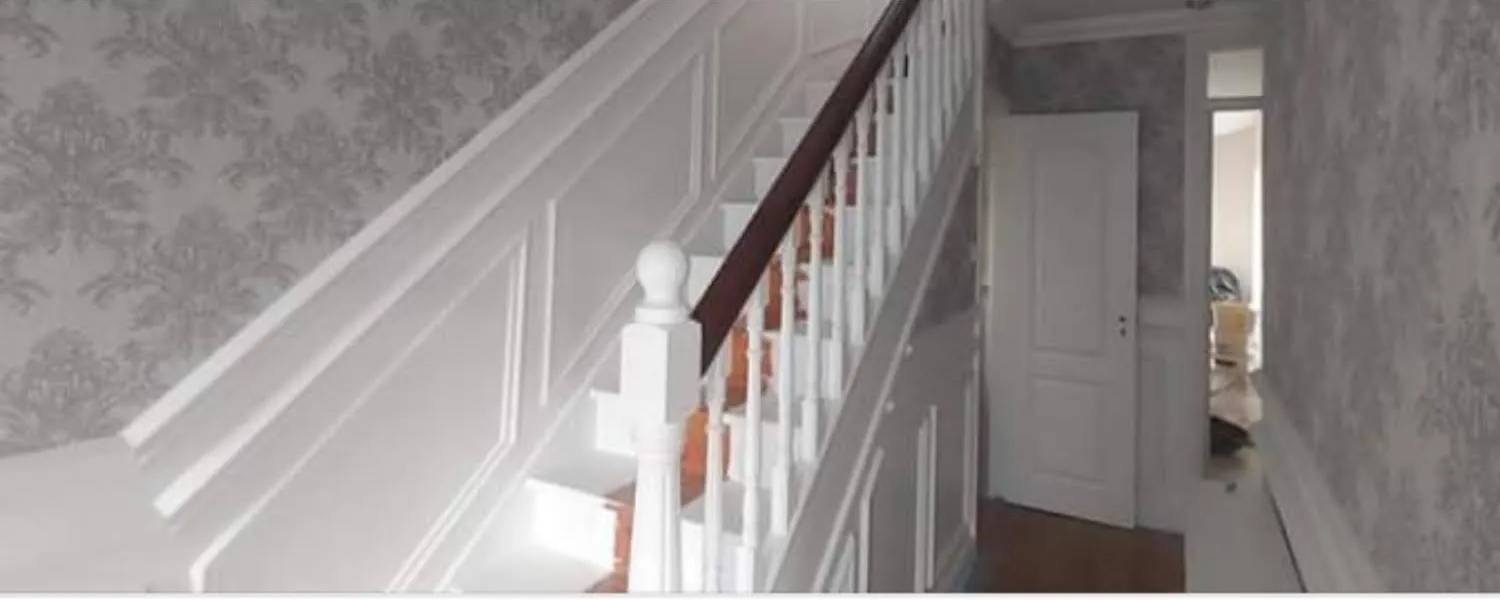 Hallway stairs with white panelling and damask wallpaper