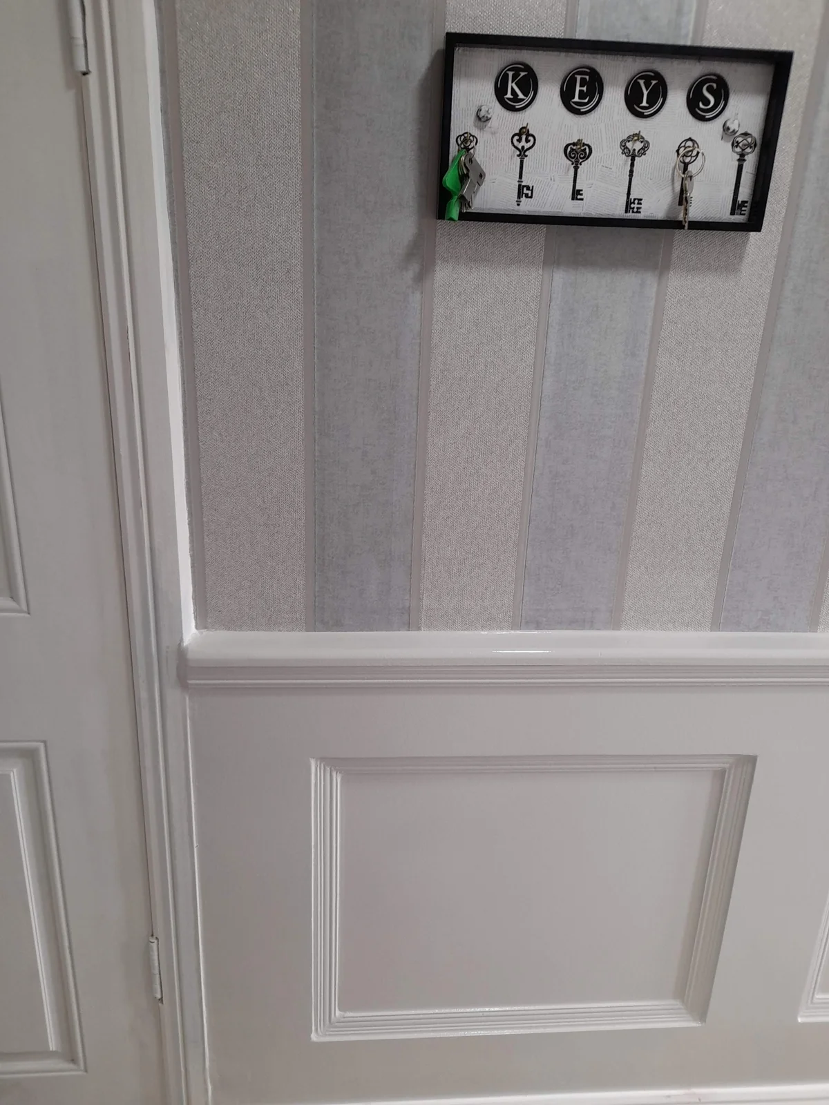 White panelling below patterned wallpaper