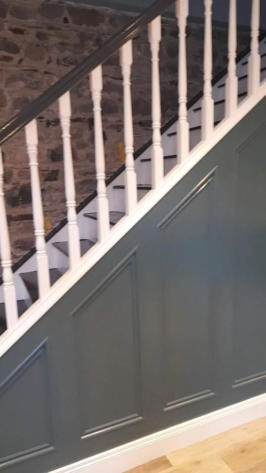 Staircase with teal decorative panelling and white spindles